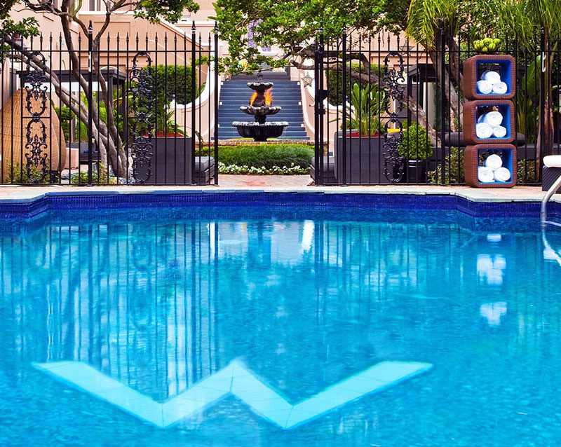 A pool with a fountain and trees in the background.