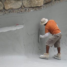 A man in an orange shirt is painting the wall.