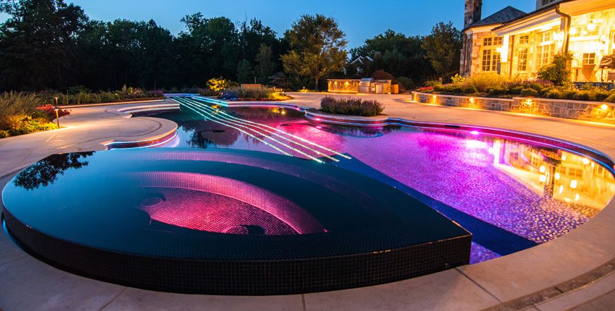 A pool with lights and a large fountain